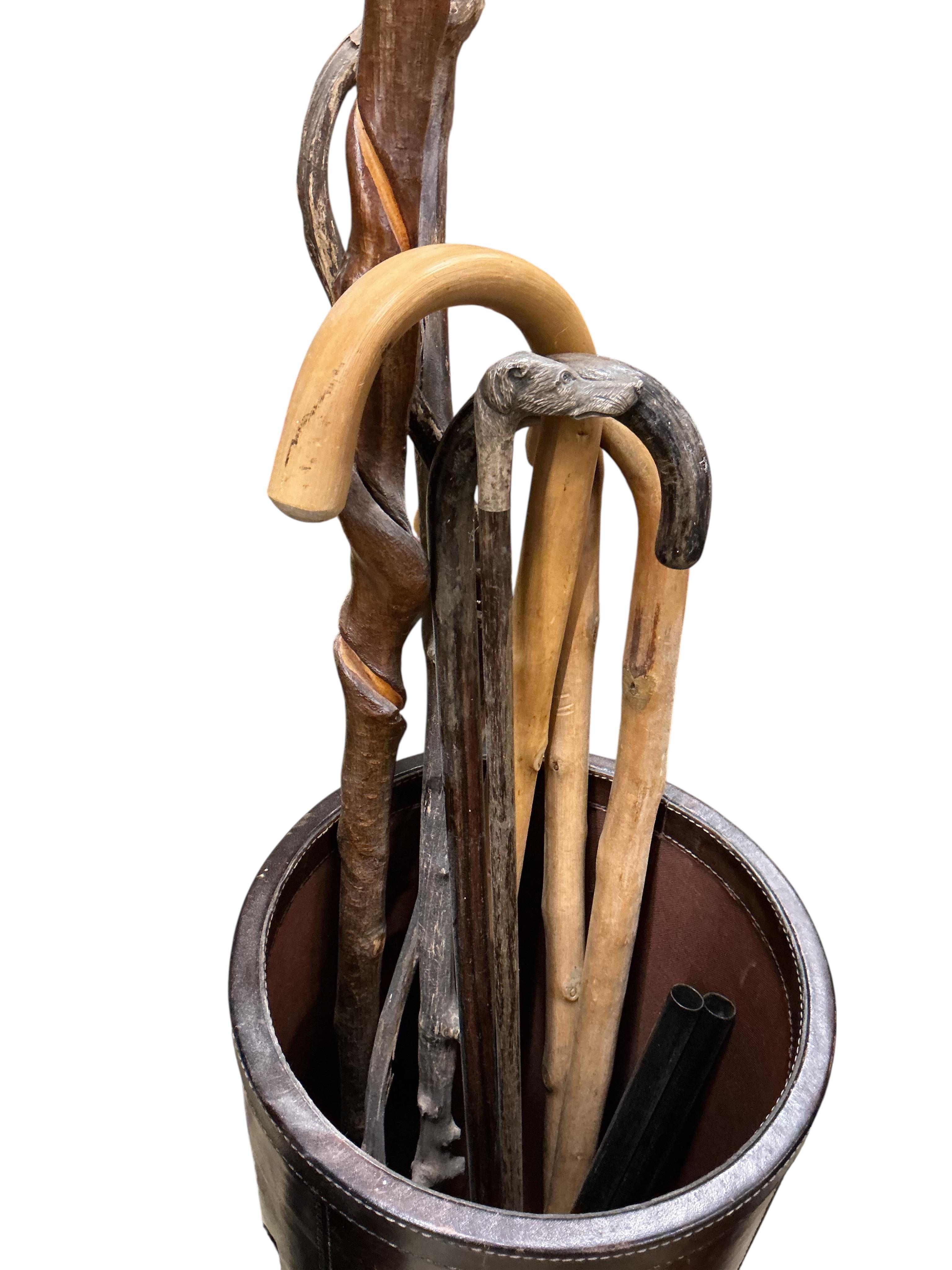 Three leather covered cylindrical stick stands and assorted sticks, largest stick stand, diameter 28cm